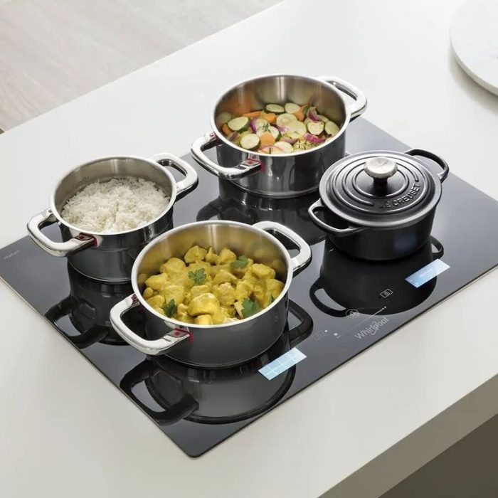 Cubierta de inducción Whirlpool con cuatro platos en preparación arroz, curry, vegetales y olla Le Creuset.