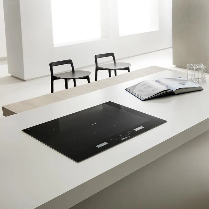 Cubierta de inducción Whirlpool integrada en cocina minimalista con libro y decoración contemporánea.