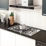 Estufa de empotrar a gas en cocina moderna con olla humeante y campana Whirlpool.