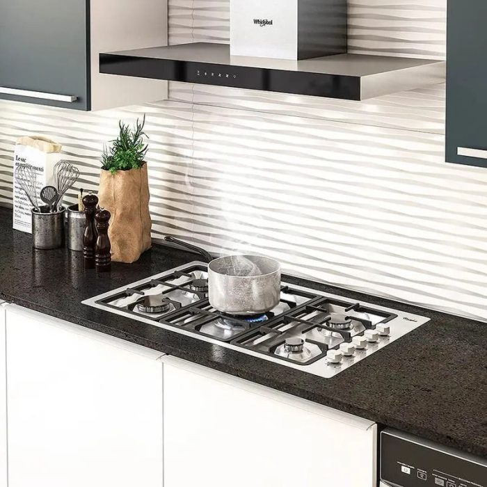 Estufa de empotrar a gas en cocina moderna con olla humeante y campana Whirlpool.