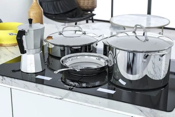 Cubierta de inducción empotrada en mesón de mármol con batería de cocina en ambiente moderno.