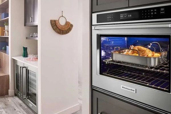 Pollo sazonado en bandeja de acero dentro de un horno eléctrico empotrado en cocina contemporánea